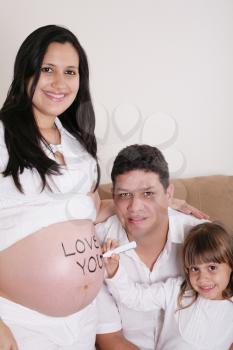 Family With Pregnant Mother Relaxing On Sofa Together with the word love you on her belly.