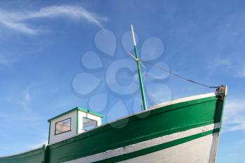 Green old fishing boat, under a blue sky