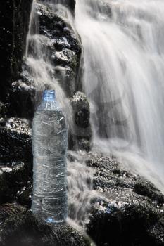 A bottle of fresh mineral water stands in waterfalls