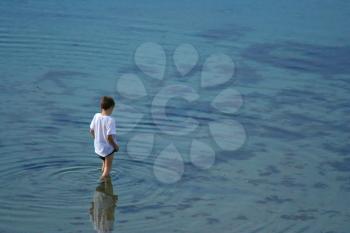 Young boy standing and looking in the clear water (hz)