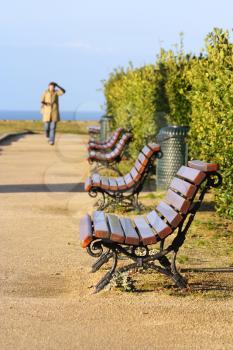Public bench near the ocean, woman in the background