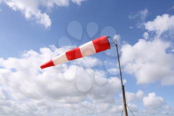 Red and white windsock blows against a blue sky