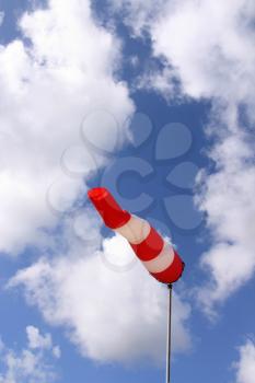 Red and white windsock blows against a blue sky