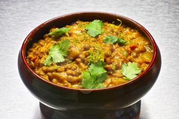 Moong Dal, indian vegetarian lentil soup, in terra cotta bowl. Aluminium background.