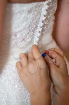 Wedding help. Hands of bridesmaids on bridal dress