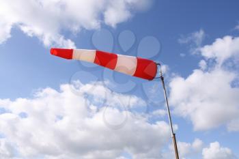 Windsock flag with red and white stripes on blue sky background