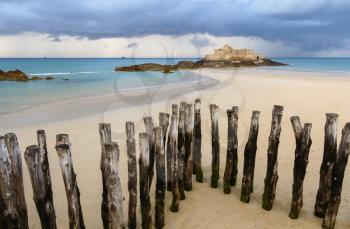 Fort National in Saint-Malo and breakwater trunks at eventail beach during low tide. Brittany, France