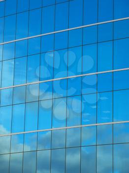 Exterior wall of modern office building with sky reflected on it
