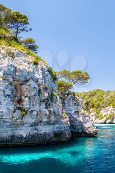 Menorca rocky coast scenery with turquoise water of Mediterranean sea near Macarella beach.