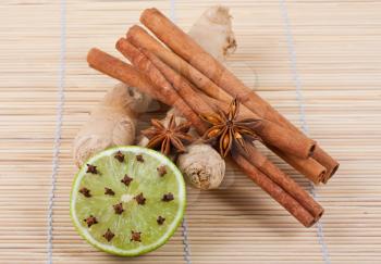 Royalty Free Photo of a Collection of Cinnamon Sticks Anise Ginger Root and a Lime