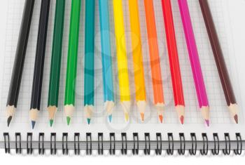 Royalty Free Photo of a Line Up of Multicolored Pencils on a Spiral Notebook