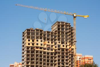 House under construction with a crane on a blue sky background