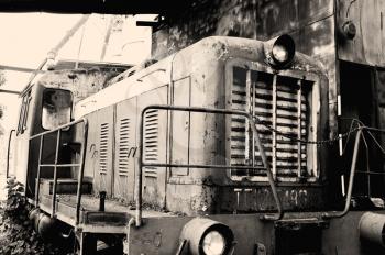 Old rusty locomotive standing on rails, closeup image, sepia