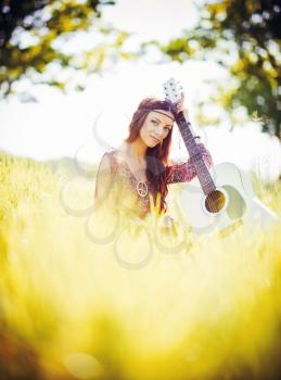 Portrait of a beautiful young hippie girl with guitar. Outdoor shot