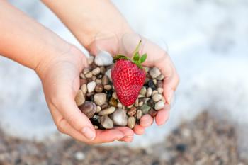 Royalty Free Photo of a Woman Holding Pebbles and a Strawberry
