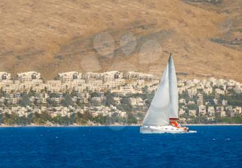 Yacht sailing in the sea near mediterranean town
