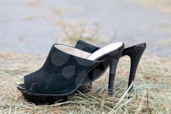 Black women shoes from shammy leather on withered straw background

