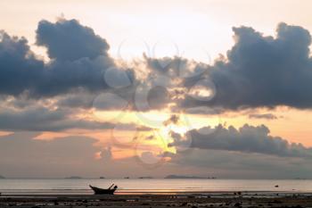 Sunset with boat in the sea, cloudy sky and low water
