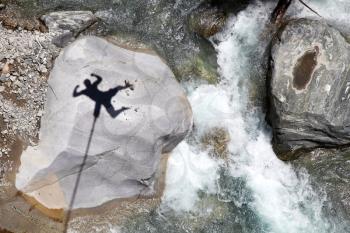 Falling bungee jumper shadow above the canyon and mountain river
