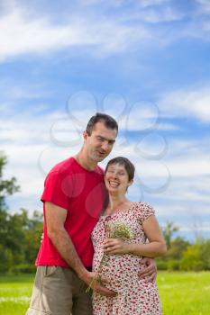 Husband hugs his pregnant wife outdoor
