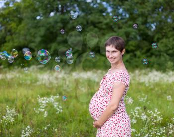 Pregnant woman with soap bubbles in the forest
