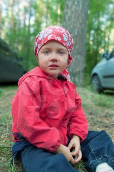 Crying little girl sitting on the ground in forest

