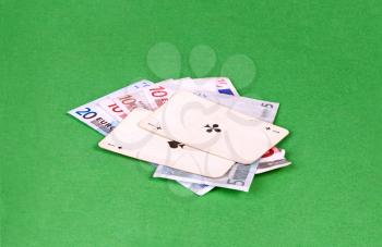 Two aces with euros on green gambling table
