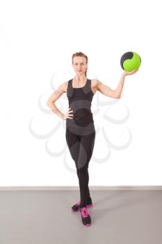 Athletic young woman training with green ball in the gym
