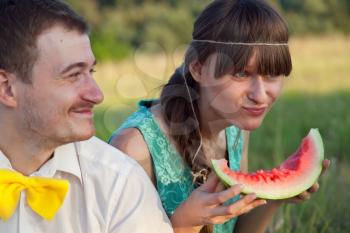 Young couple eating watermelon at picnic
