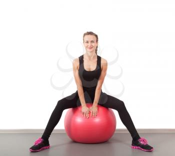 Athletic young woman on red ball in the gym
