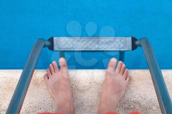 Man's legs and ladder near the swimming pool