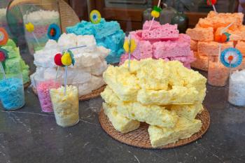 Yellow and multicolor meringue cakes in pile on the wooden straw dish
