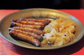 Nuremberg sausages with cabbage and spices on metal plate
