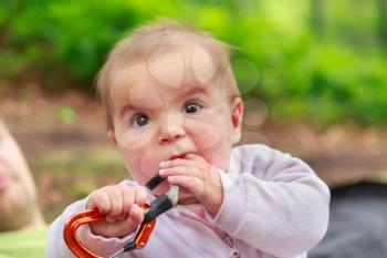 Baby girl eating climbing equipment quickdraw
