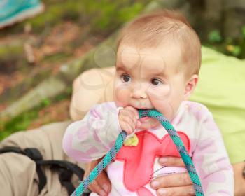 Baby girl eating climbing rope outdoor
