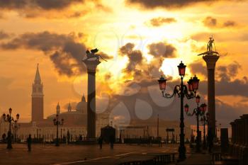 Statues on columns, gondola service and lanterns at sunset near San Marco Campanile, Venice, Italy
