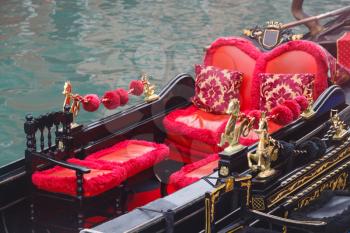 Golden figurines and red chairs on gondola near pier
