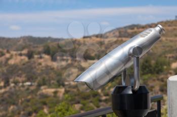 Spyglass and nature landscape with the hills and blue sky
