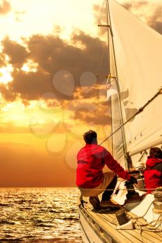 People on sailing boat in the sea at sunset
