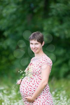 Pregnant woman with chamomile in the forest
