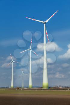 Rotating windmill blades in cloudy blue sky
