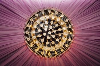 Golden chandelier with violet curtain, closeup view
