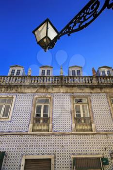 Blue portuguese tiles on house wall with cracks and latnern in the sky
