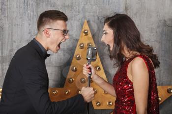 Young girl in red cocktail dress and guy singing with vintage microphone

