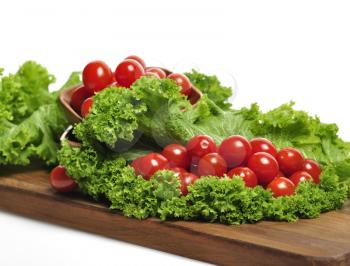 Royalty Free Photo of Tomatoes and Lettuce on a Cutting Board