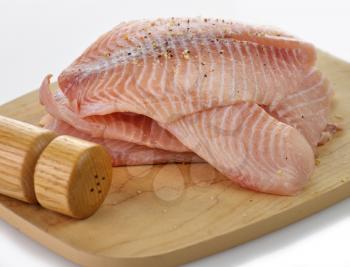 tilapia fillets on a cutting board with spices