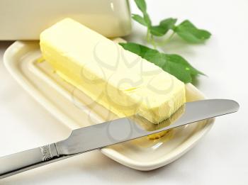 butter on white butterdish with knife , close up
