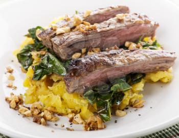 flank steak with mashed plantain , collard greens and ginger peanuts