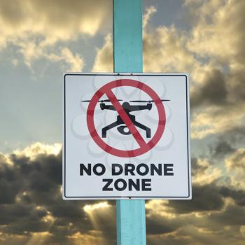 No Drone zone sign against the sky at sunset
