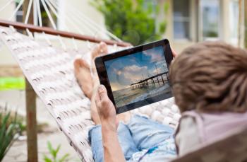 Man using a tablet computer while relaxing in a hammock